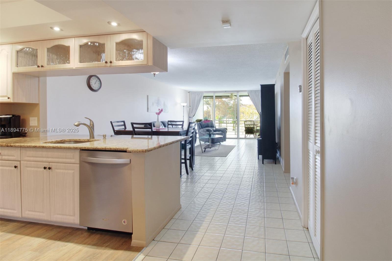 A kitchen with granite countertops and stainless steel appliances opens into a tiled living area — 605 Oaks Dr # 305, Pompano Beach FL 33069, POMPANO BEACH, FL
