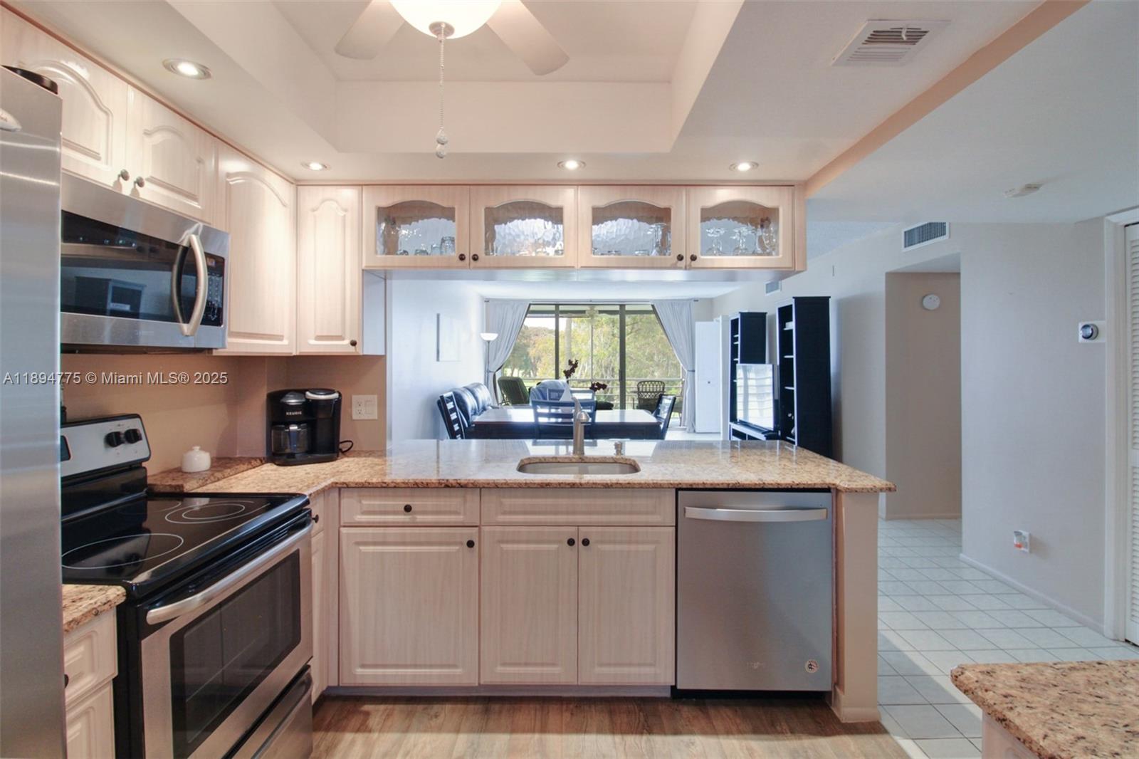 A kitchen features light wood cabinets, granite countertops, stainless steel appliances, and a breakfast bar — 605 Oaks Dr # 305, Pompano Beach FL 33069, POMPANO BEACH, FL
