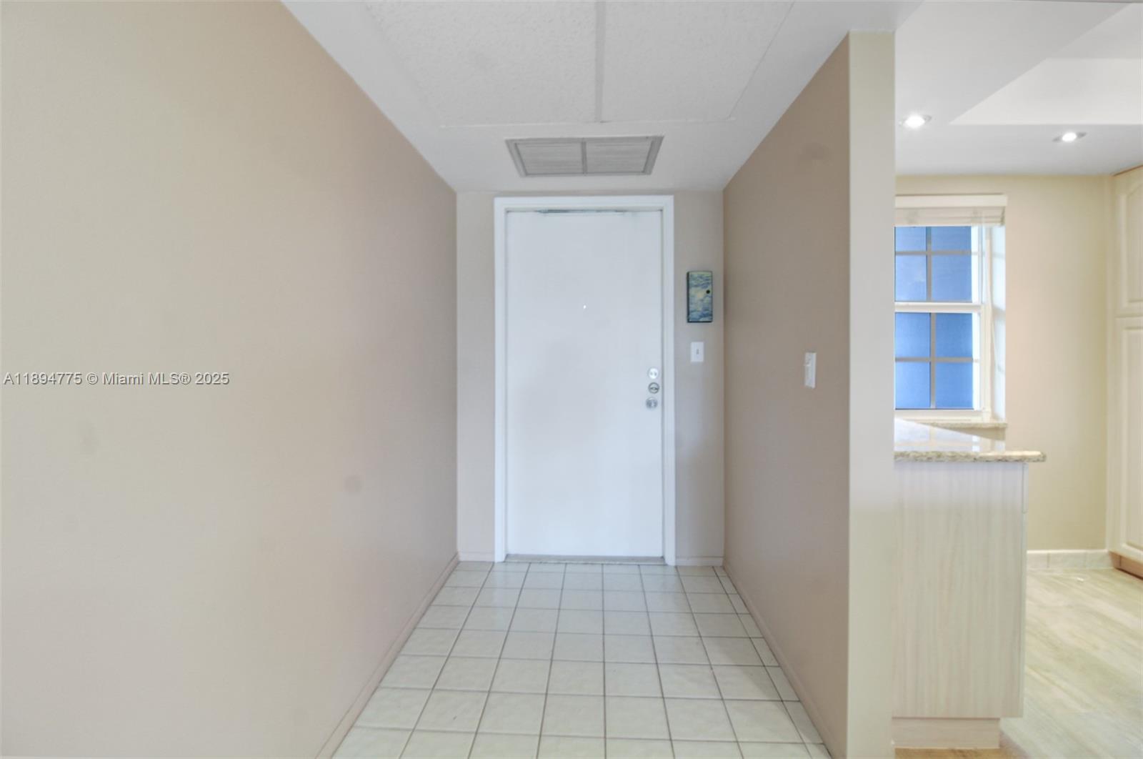 A tiled entryway leads to a white door with beige walls and a ceiling vent — 605 Oaks Dr # 305, Pompano Beach FL 33069, POMPANO BEACH, FL