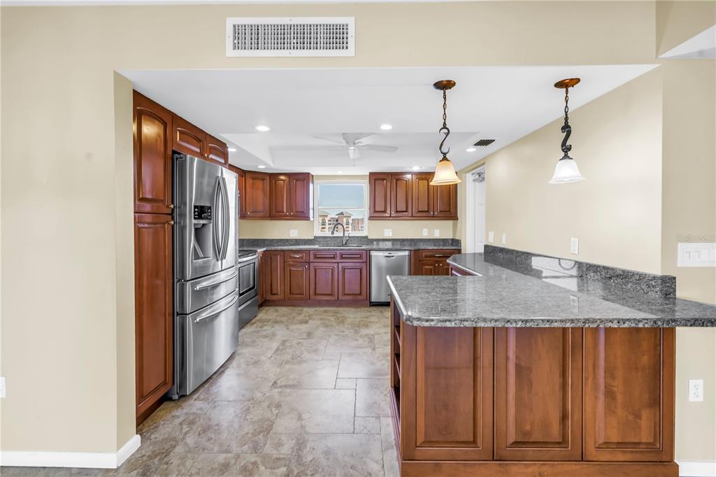 A kitchen features dark wood cabinets, granite countertops, stainless steel appliances, and tile flooring — 5108 BRITTANY DRIVE S UNIT 908, ST PETERSBURG, FL