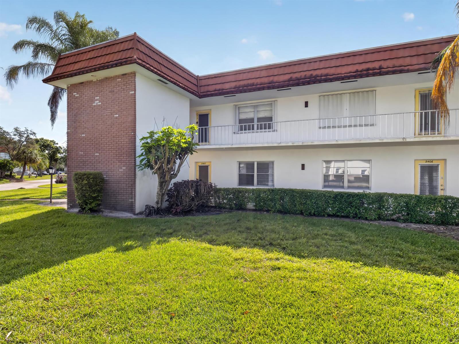 A two-story apartment building features a brick facade, white walls, and a red roof — 1225 NW 21st Street # 2407, Stuart FL 34994, STUART, FL