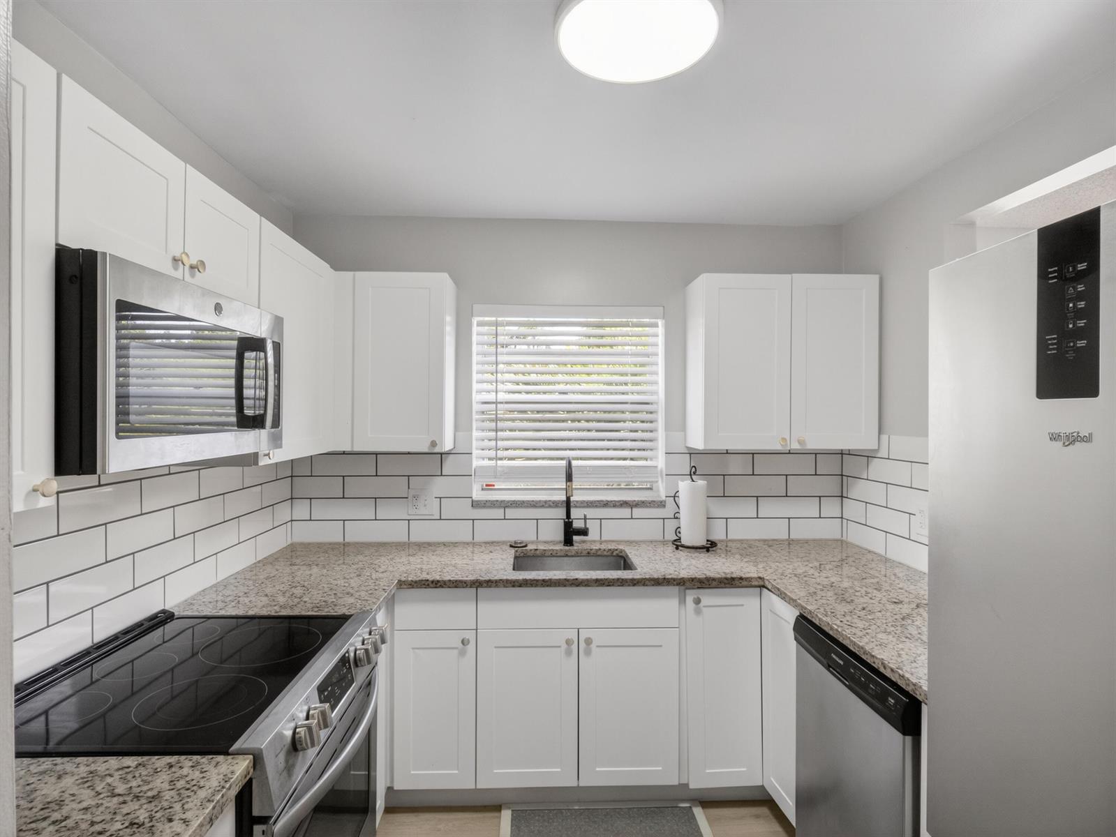 A kitchen with white cabinets, granite countertops, stainless steel appliances, and a subway tile backsplash — 1225 NW 21st Street # 2407, Stuart FL 34994, STUART, FL