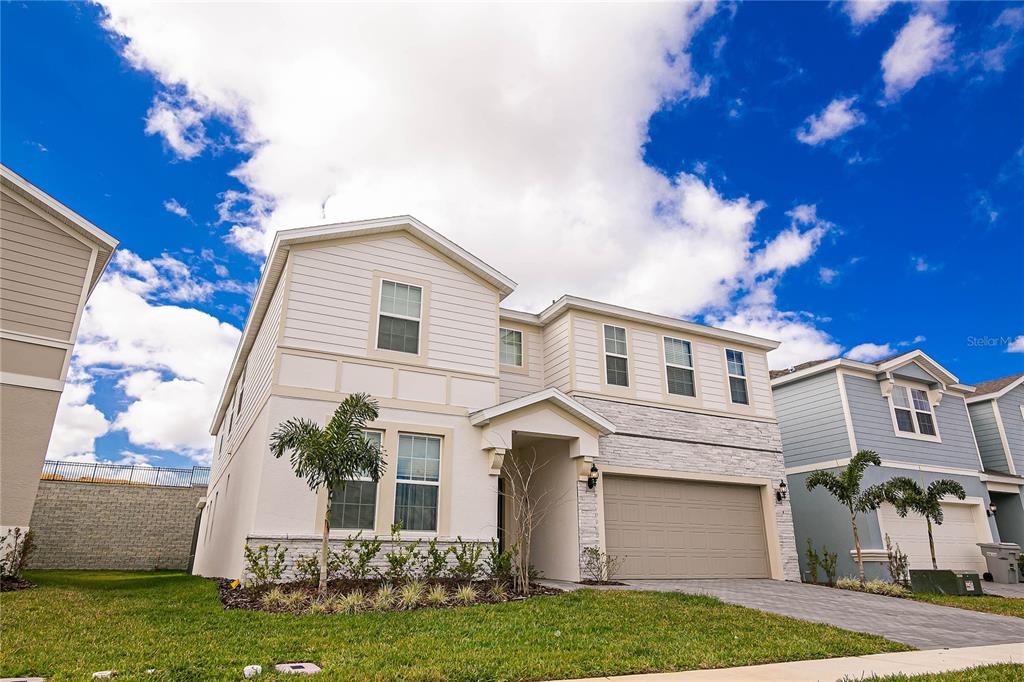 A two-story suburban house with a light-colored facade, stone accents, and a two-car garage — 2280 LELANI CIRCLE, DAVENPORT, FL