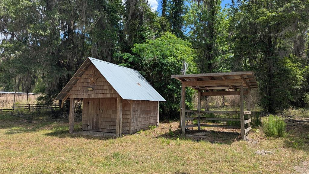 A wooden shed with a metal roof stands next to an open-sided shelter outdoors — TBD NW 71ST TERRACE, GAINESVILLE, FL