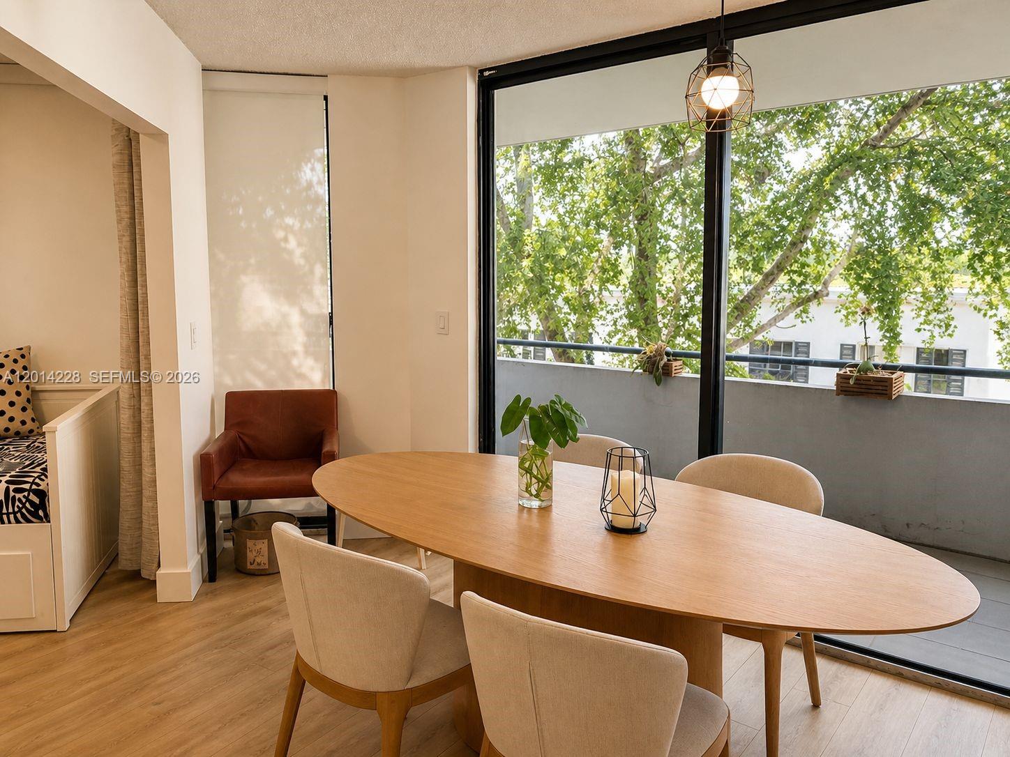 A dining area features an oval wooden table, light-colored chairs, and a balcony view — 21075 NE 34th Ave # 2, Aventura FL 33180, AVENTURA, FL