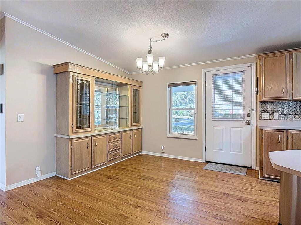 A dining area features wood-look flooring, a built-in hutch, a chandelier, and a glass-paneled door — 25533 BELLE HELENE, LEESBURG, FL
