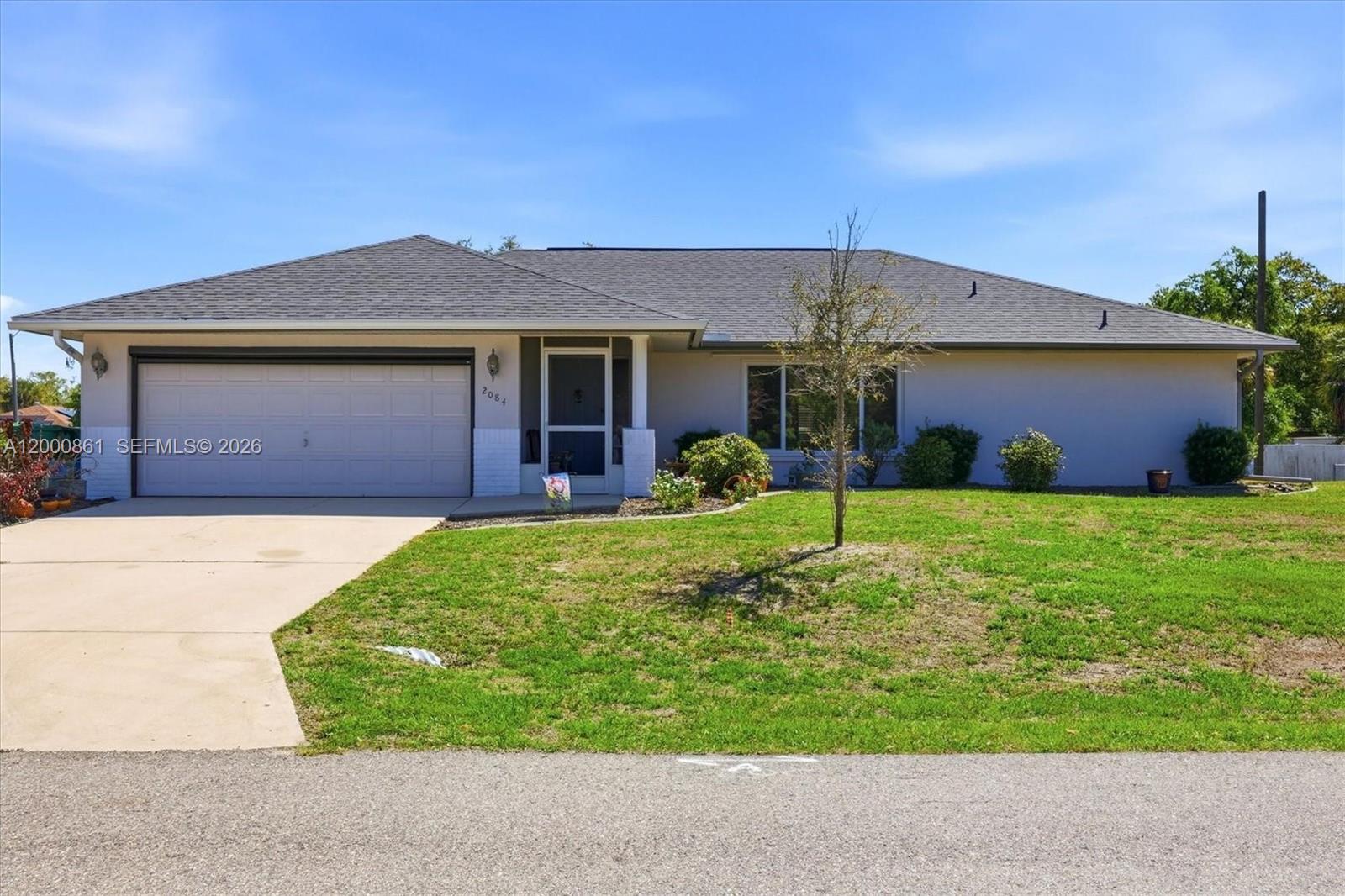A single-story house with a gray roof, white stucco exterior, and an attached two-car garage — PORT CHARLOTTE, FL