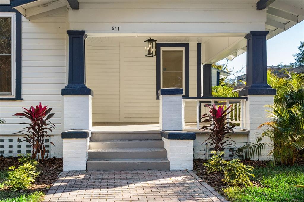 A white house exterior features a covered front porch with dark blue columns and steps — 511 E FRANCES AVENUE, TAMPA, FL