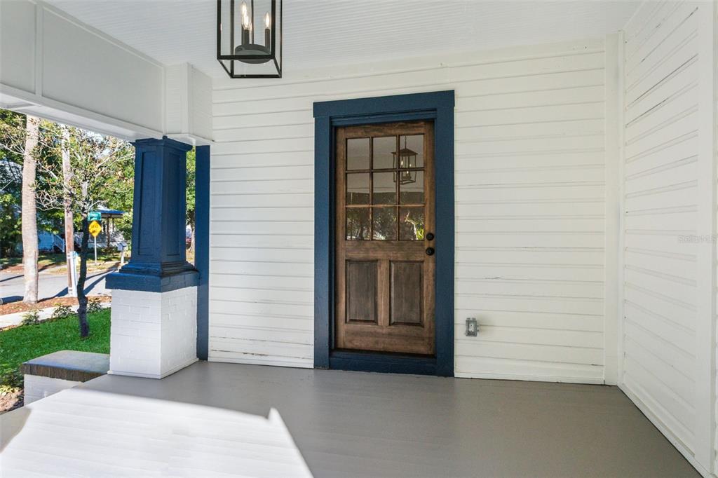 A covered front porch features white horizontal siding, a dark blue door frame, and a wooden door — 511 E FRANCES AVENUE, TAMPA, FL
