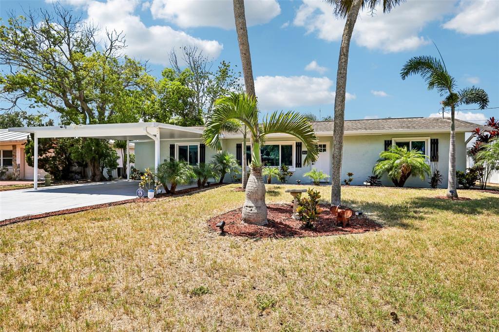 A single-story house with a carport, palm trees, and a front lawn under a blue sky — 14124 KULIG COURT, HUDSON, FL