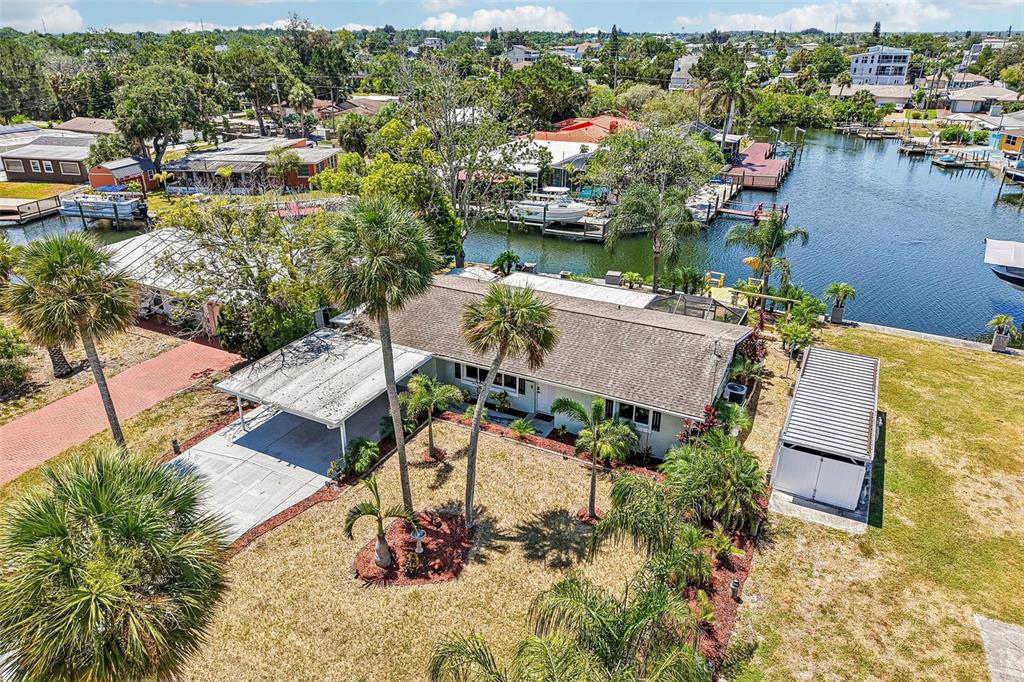 An aerial view shows a single-story house with a carport, palm trees, and a canal — 14124 KULIG COURT, HUDSON, FL