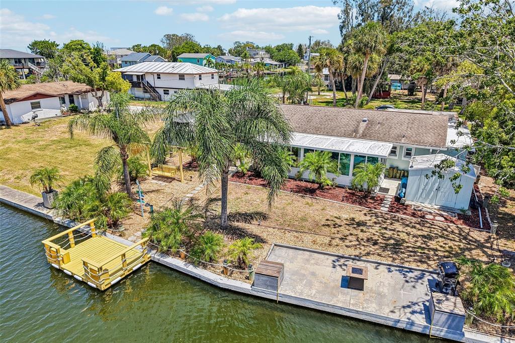 An aerial view of a waterfront house with a wooden dock, patio, and palm trees — 14124 KULIG COURT, HUDSON, FL