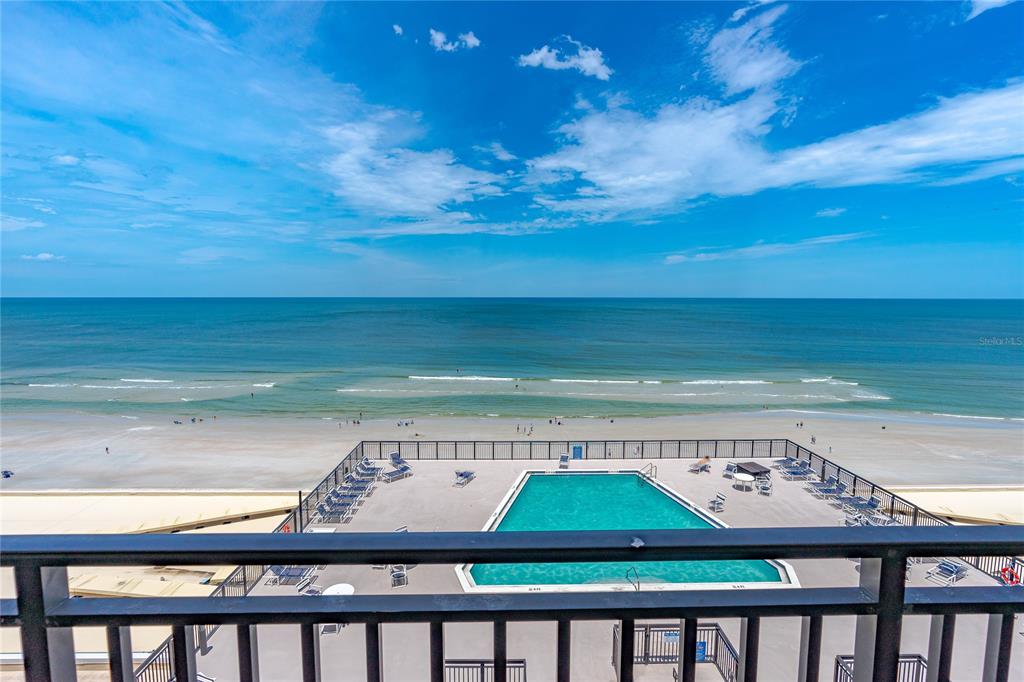 An elevated view of a swimming pool deck overlooking a sandy beach and the ocean — 4139 S. ATLANTIC AVENUE UNIT B504, NEW SMYRNA BEACH, FL
