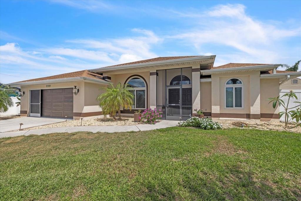 A single-story house with a brown garage, a screened entryway, and a front lawn — 6308 ZENO CIRCLE, PORT CHARLOTTE, FL