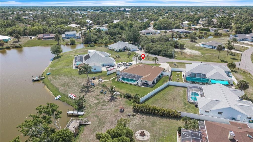 An aerial view shows a house with a pool and screened lanai beside a lake — 6308 ZENO CIRCLE, PORT CHARLOTTE, FL