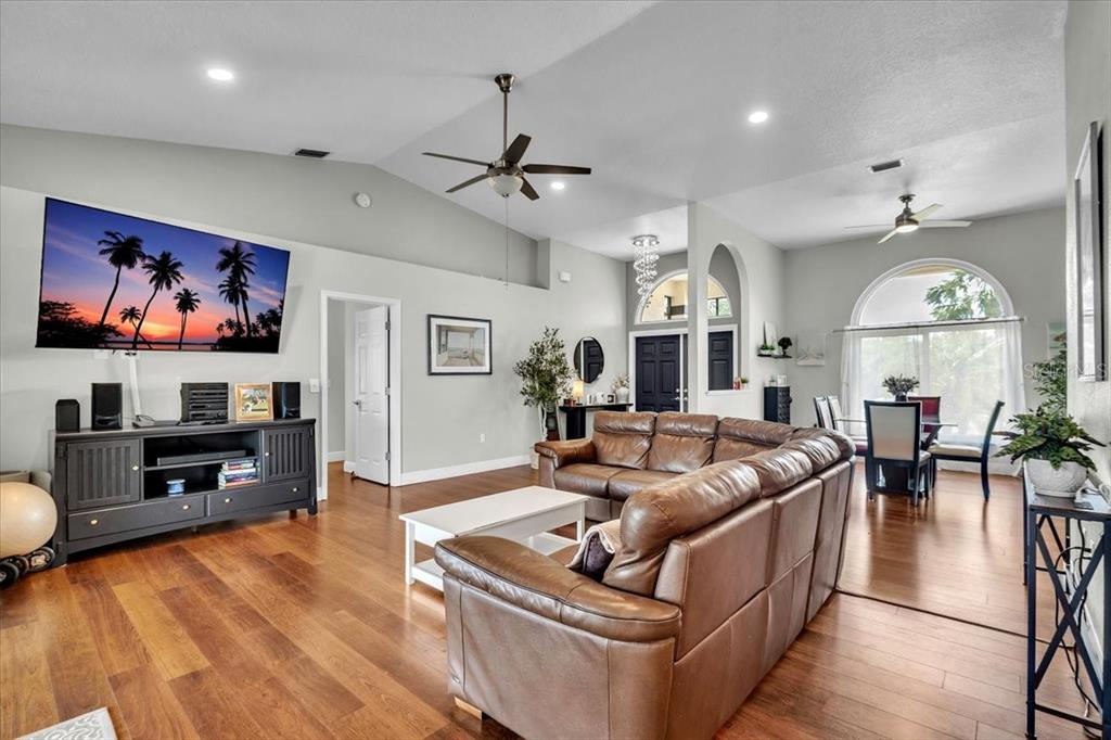 A living room with wood floors, a brown leather sofa, and a wall-mounted television — 6308 ZENO CIRCLE, PORT CHARLOTTE, FL