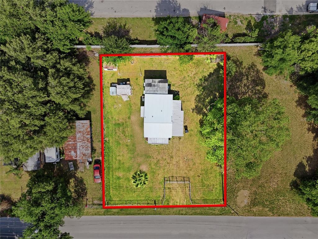 An aerial view shows a house with a metal roof centered on a fenced lot — 1705 DELAWARE AVENUE, ST CLOUD, FL