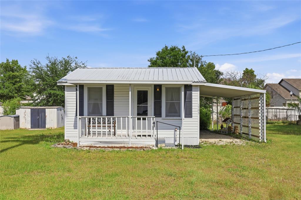 A small white house with a metal roof, front porch, and attached carport — 1705 DELAWARE AVENUE, ST CLOUD, FL