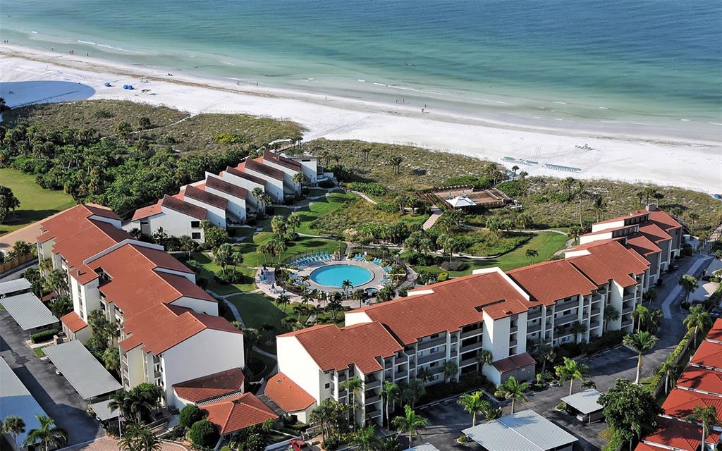 An aerial view of a beachfront condominium complex with a central pool and parking areas — 6234 MIDNIGHT PASS ROAD UNIT 307, SARASOTA, FL
