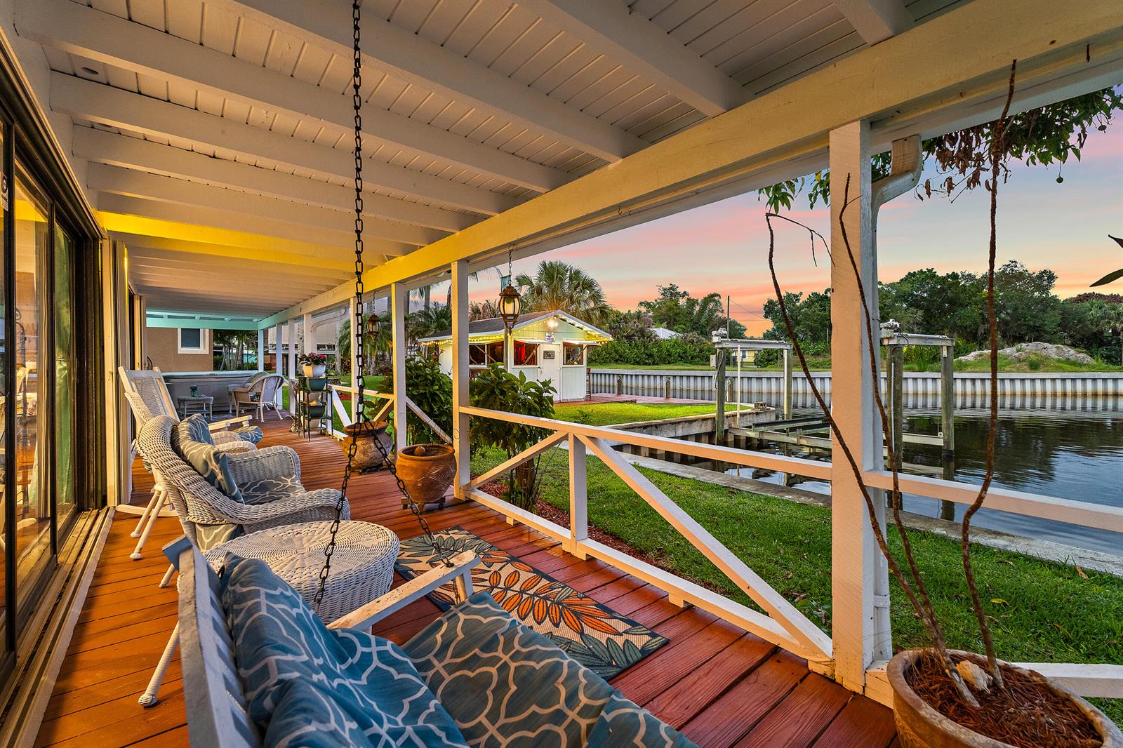 A covered wooden deck overlooks a canal with a small shed and boat lift — 715 SW Rustic Circle, Stuart FL 34997, STUART, FL