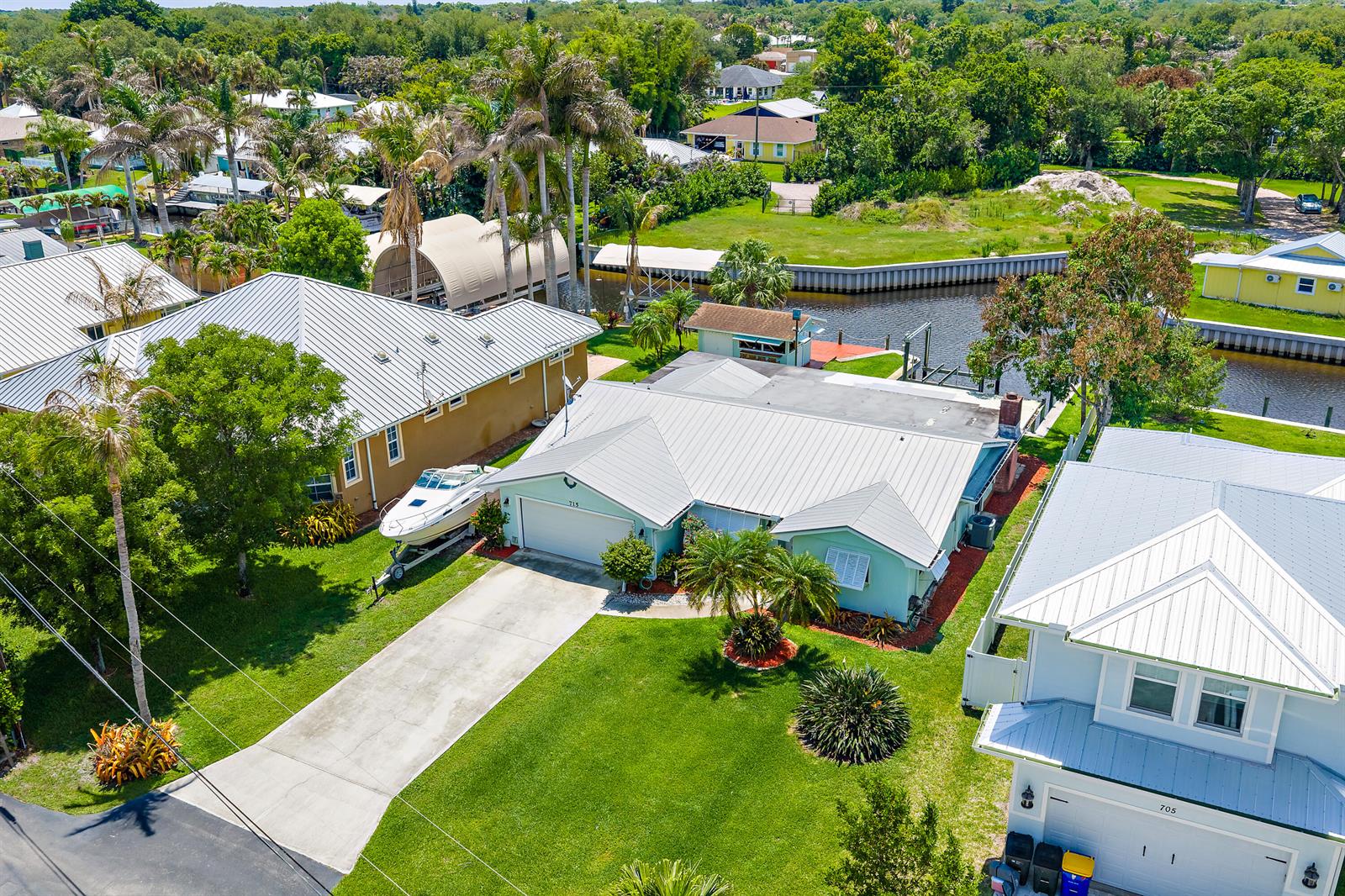 An aerial view shows a light green house with a metal roof and a boat — 715 SW Rustic Circle, Stuart FL 34997, STUART, FL