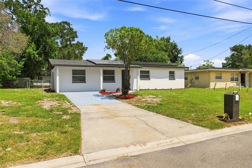 A white single-story house with a concrete driveway and solar panels on the roof — 1916 MARVY AVENUE, TAMPA, FL