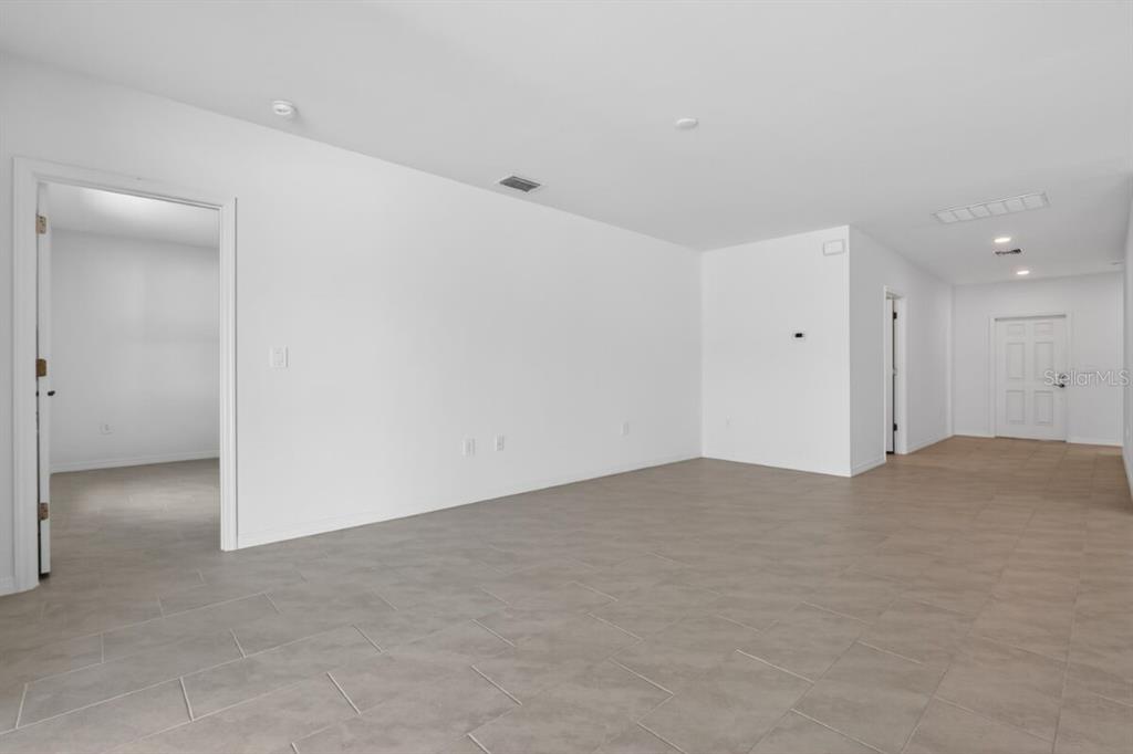 An empty room with white walls, tile flooring, and doorways leading to other spaces — 9509 VIBRANT LANE, VENICE, FL