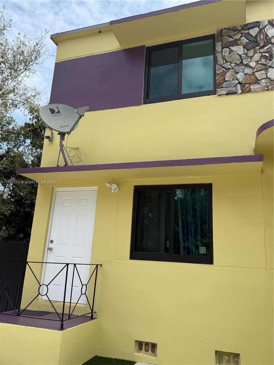 A two-story yellow exterior features a white door, sliding windows, and a satellite dish — 5501 NW Miami Ct, Miami FL 33127, MIAMI, FL