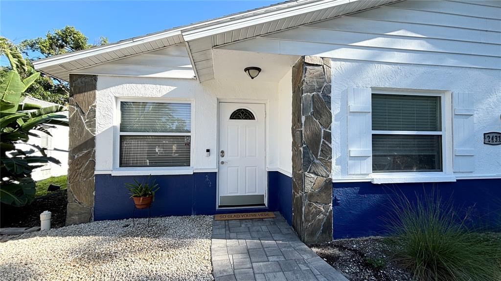 The exterior of a house features white siding, blue lower walls, and stone accents — 2431 LOMA LINDA STREET, SARASOTA, FL