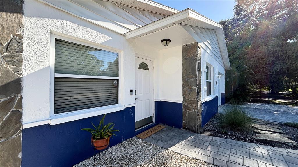 The exterior of a house features white stucco walls, blue trim, and stone accents — 2431 LOMA LINDA STREET, SARASOTA, FL