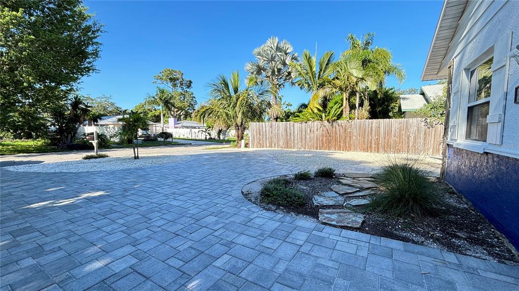 A paved driveway leads to a backyard with a wooden fence and tropical landscaping — 2431 LOMA LINDA STREET, SARASOTA, FL