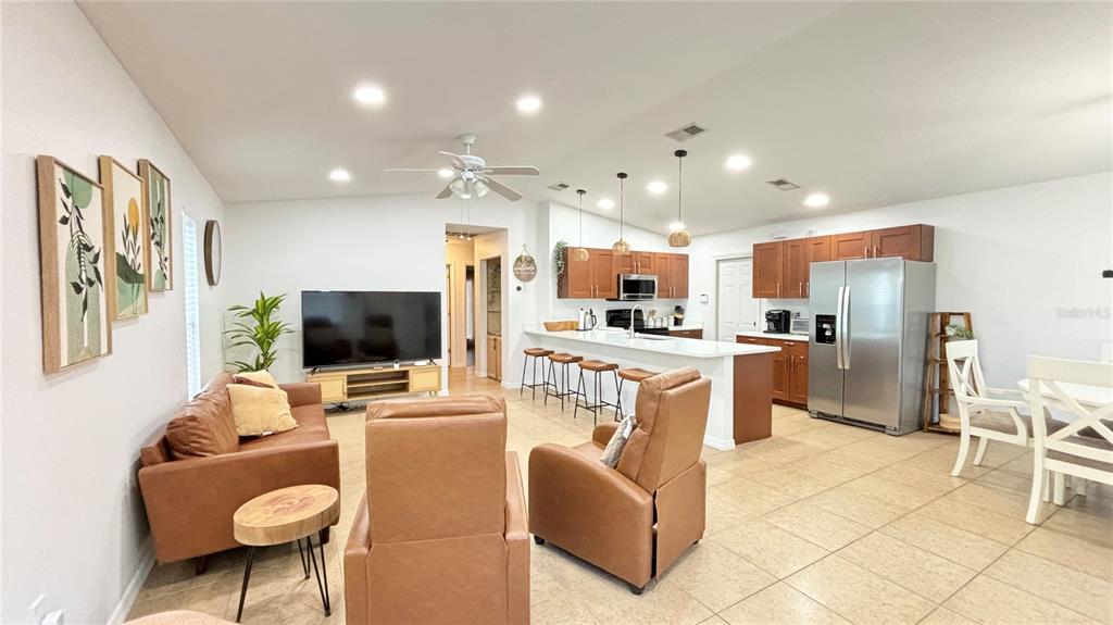 An open-concept living room and kitchen featuring tile floors, brown leather furniture, and wooden cabinetry — 2431 LOMA LINDA STREET, SARASOTA, FL