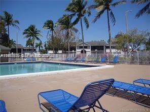 A swimming pool with blue lounge chairs on a deck surrounded by palm trees — 468 NE 206th Ln # 107, Miami FL 33179, MIAMI, FL