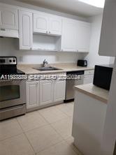 A kitchen features white cabinets, stainless steel appliances, and light-colored tile flooring — 468 NE 206th Ln # 107, Miami FL 33179, MIAMI, FL