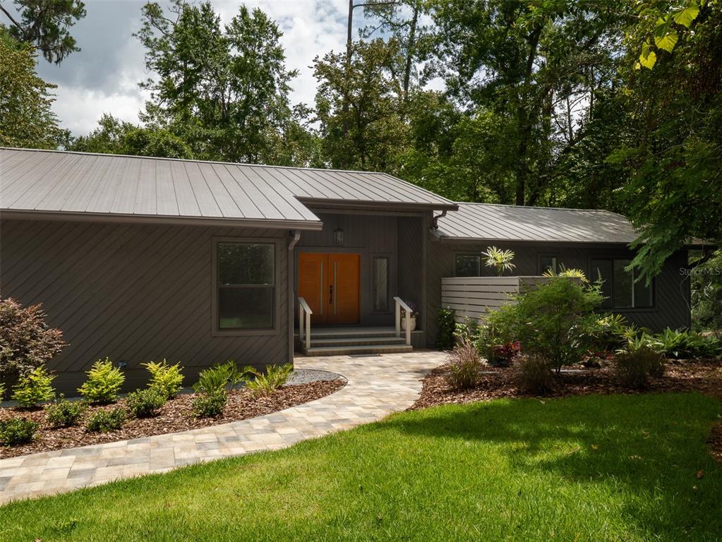 A dark-sided house with a metal roof and a stone walkway leading to the entrance — 3104 NW 21ST AVENUE, GAINESVILLE, FL