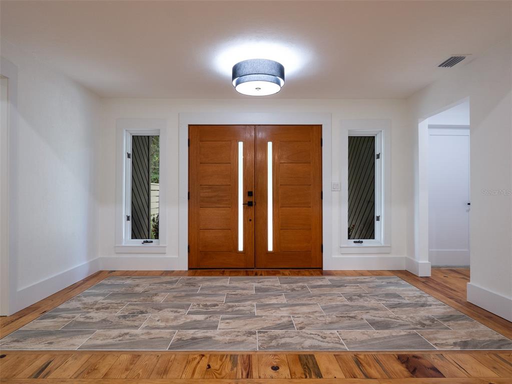 An entryway features double wood doors with vertical glass panels, tile flooring, and hardwood floors — 3104 NW 21ST AVENUE, GAINESVILLE, FL