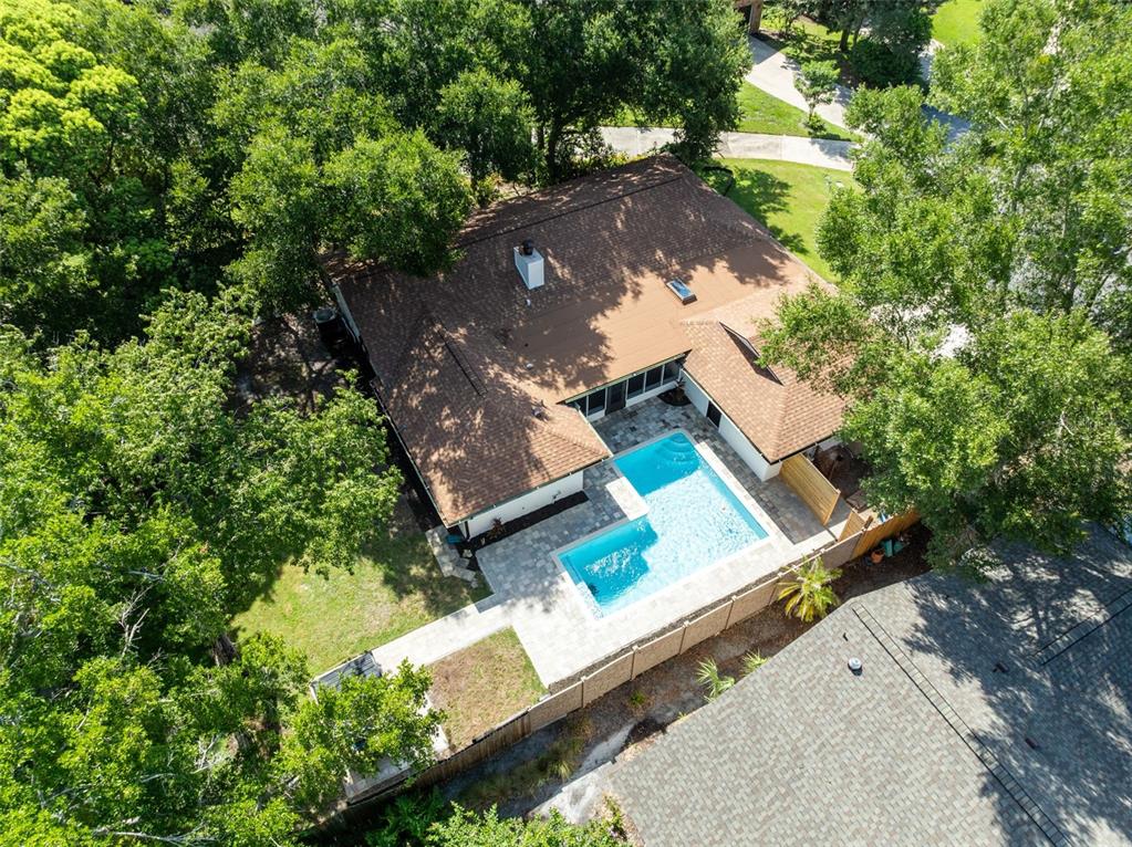An aerial view shows a house with a brown roof, a pool, and surrounding trees — 120 TRAFALGAR PLACE, LONGWOOD, FL