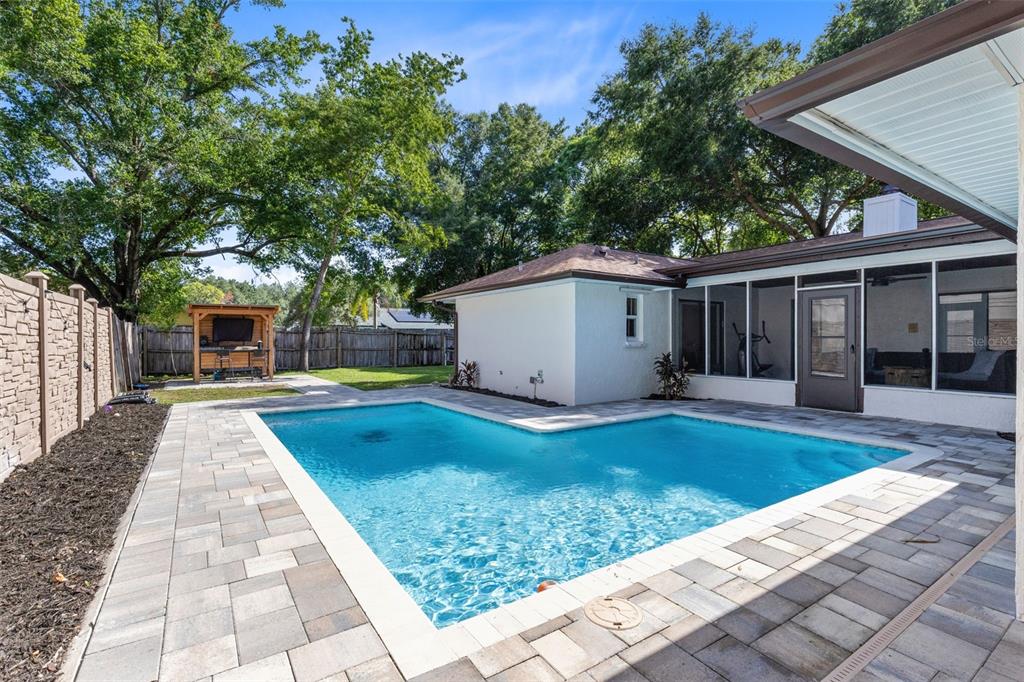 A backyard features an L-shaped swimming pool, a paved patio, and a covered outdoor structure — 120 TRAFALGAR PLACE, LONGWOOD, FL