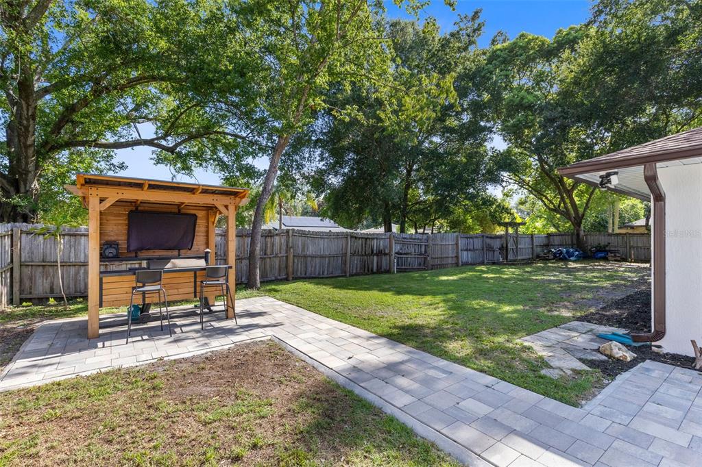 A backyard features a wooden outdoor bar structure, a paved patio, and a wooden fence — 120 TRAFALGAR PLACE, LONGWOOD, FL