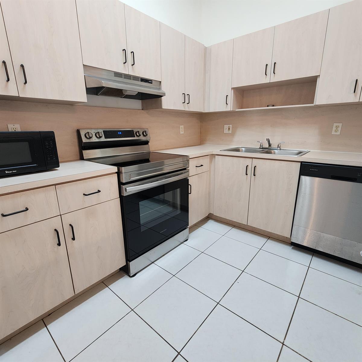 A kitchen with light wood cabinets, white tile flooring, and stainless steel appliances — 500 NE 3rd Street # 109, FL 33009, FL