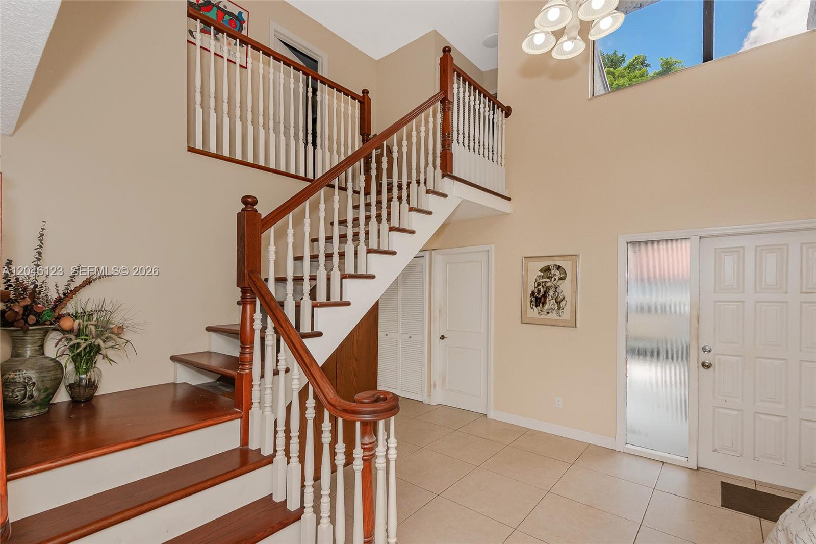 A foyer features a wooden staircase with white balusters, tile flooring, and a high ceiling — 8890 SW 133rd Pl # A, Miami FL 33186, MIAMI, FL