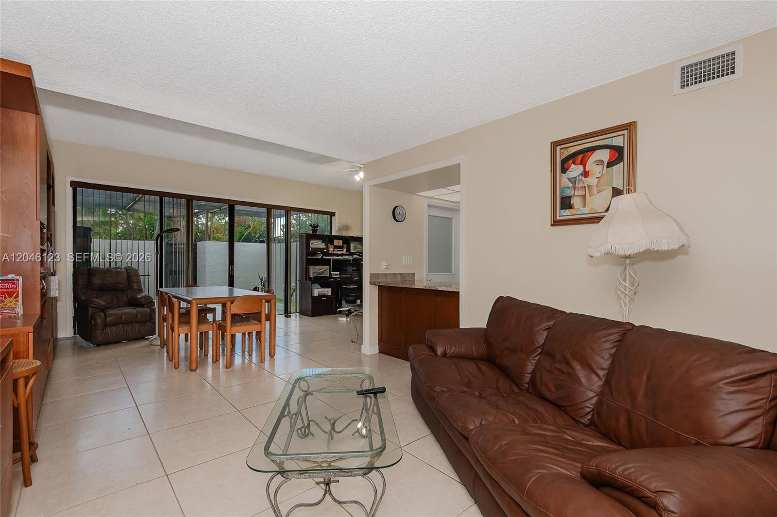 A living room features tile flooring, a brown leather sofa, and a dining area — 8890 SW 133rd Pl # A, Miami FL 33186, MIAMI, FL