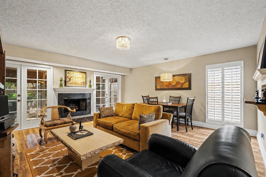 A living and dining area features a fireplace, a gold sofa, and wood-look flooring — 3053 S CONCORDIA AVENUE UNIT A, TAMPA, FL