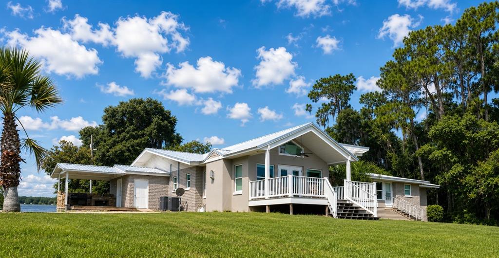 A single-story house with a metal roof, white railings, and a deck overlooking a lake — 10893 SE 141 AVENUE ROAD, OCKLAWAHA, FL