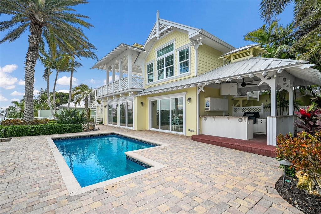 A yellow two-story house features a swimming pool, a covered patio, and a spiral staircase — 8321 MARINA DRIVE, HOLMES BEACH, FL