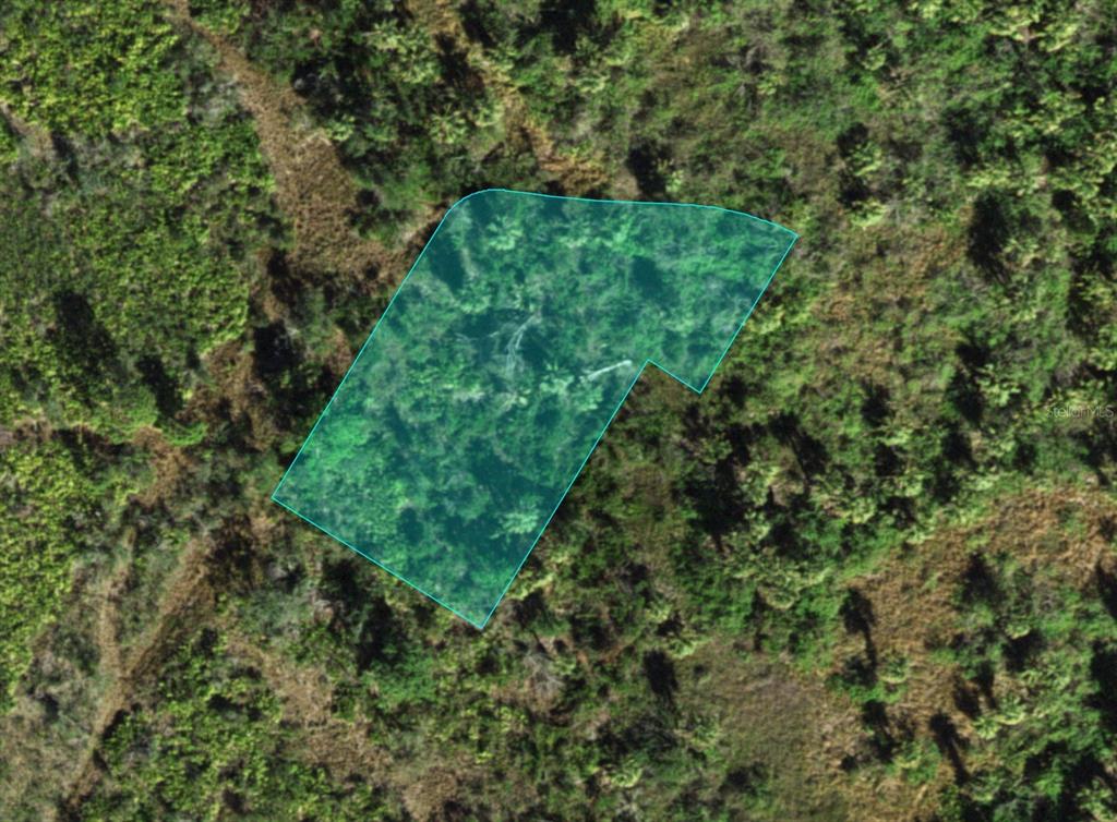 An aerial view shows a plot of land highlighted in blue against a wooded background — 1516 CASABELLA TERRACE, PUNTA GORDA, FL