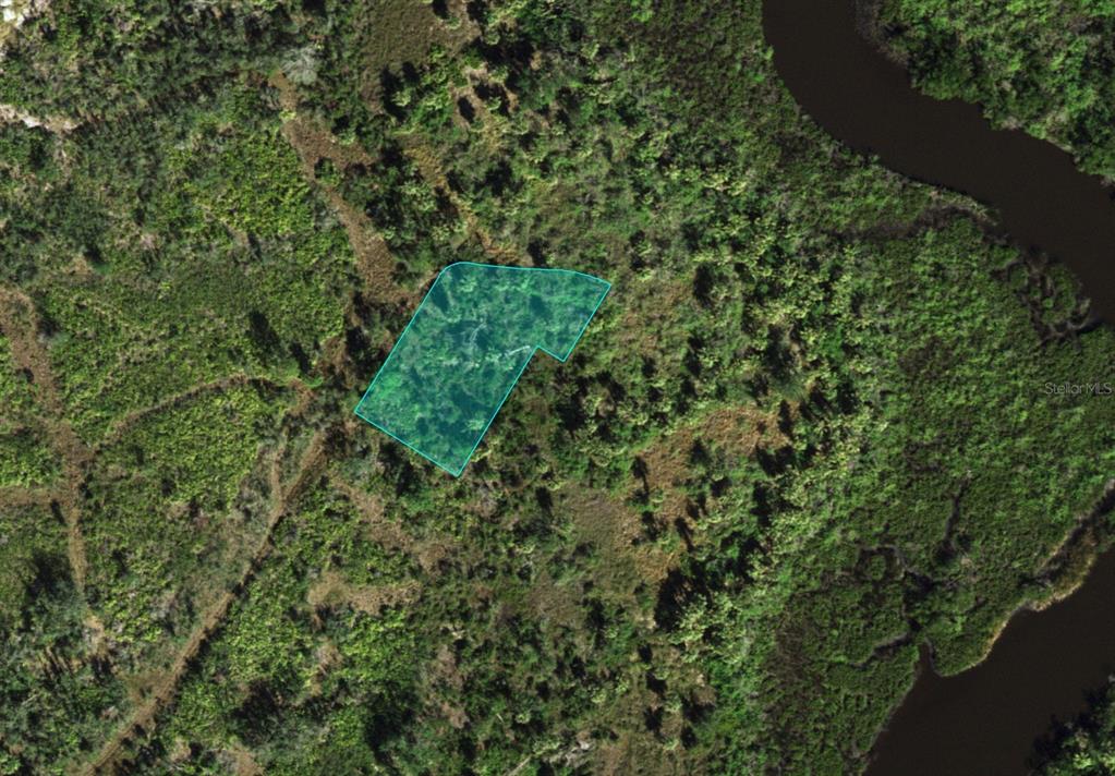 An aerial view shows a highlighted plot of land surrounded by dense forest and water — 1516 CASABELLA TERRACE, PUNTA GORDA, FL