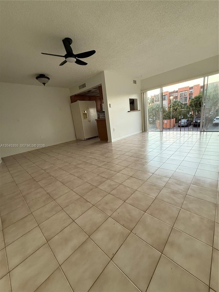 An open-concept living area features light-colored tile flooring, a ceiling fan, and a sliding glass door — 9390 W Flagler St # 224C, Miami FL 33174, MIAMI, FL