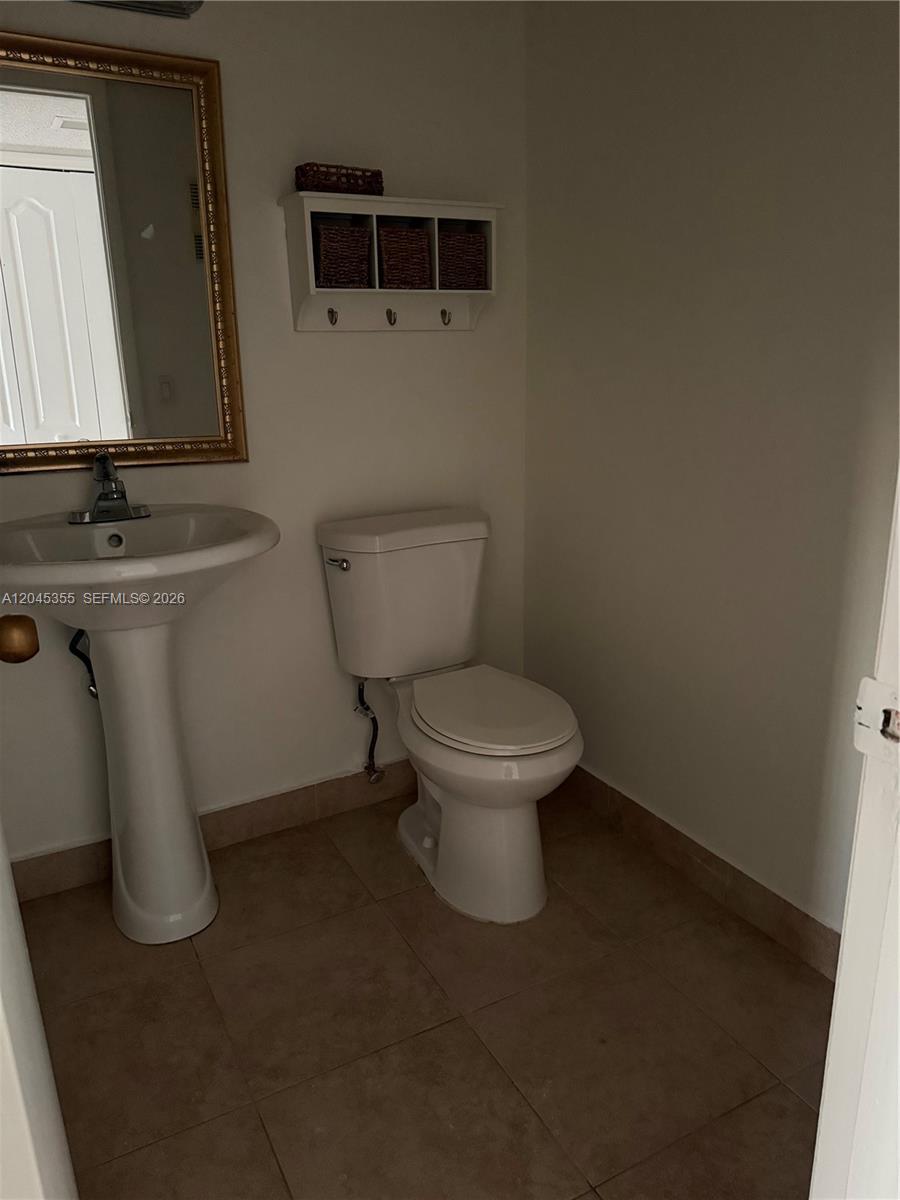 A bathroom features a pedestal sink, a toilet, and a wall-mounted storage shelf — 9390 W Flagler St # 224C, Miami FL 33174, MIAMI, FL