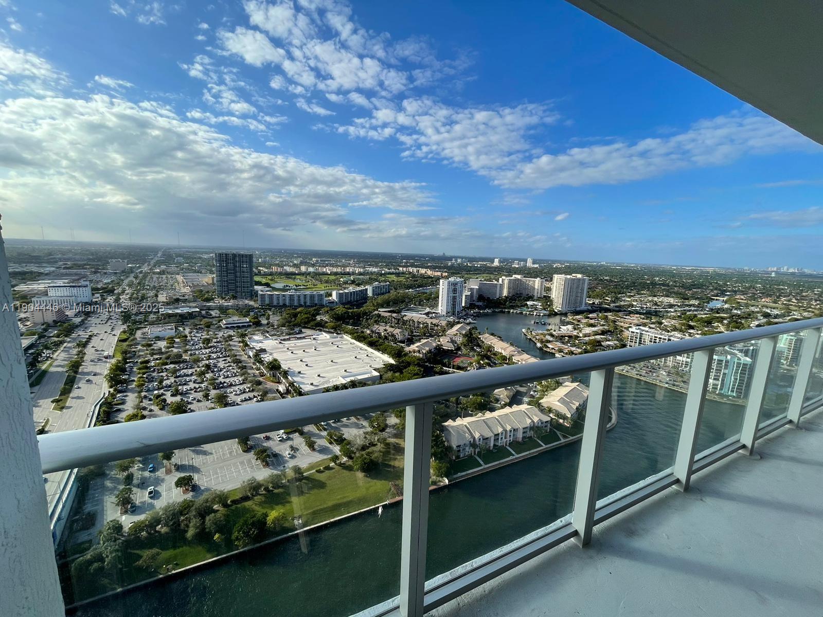 A high-rise balcony overlooks a suburban landscape with a canal, parking lots, and apartment buildings — 4010 S Ocean Dr # R3306, Hollywood FL 33019, HOLLYWOOD, FL